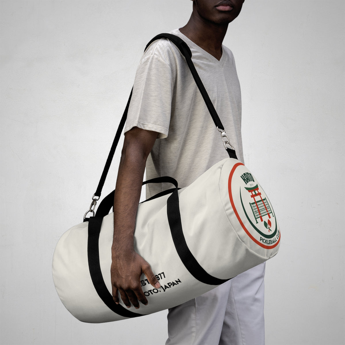 Person holding a white duffel bag with branding against a plain background