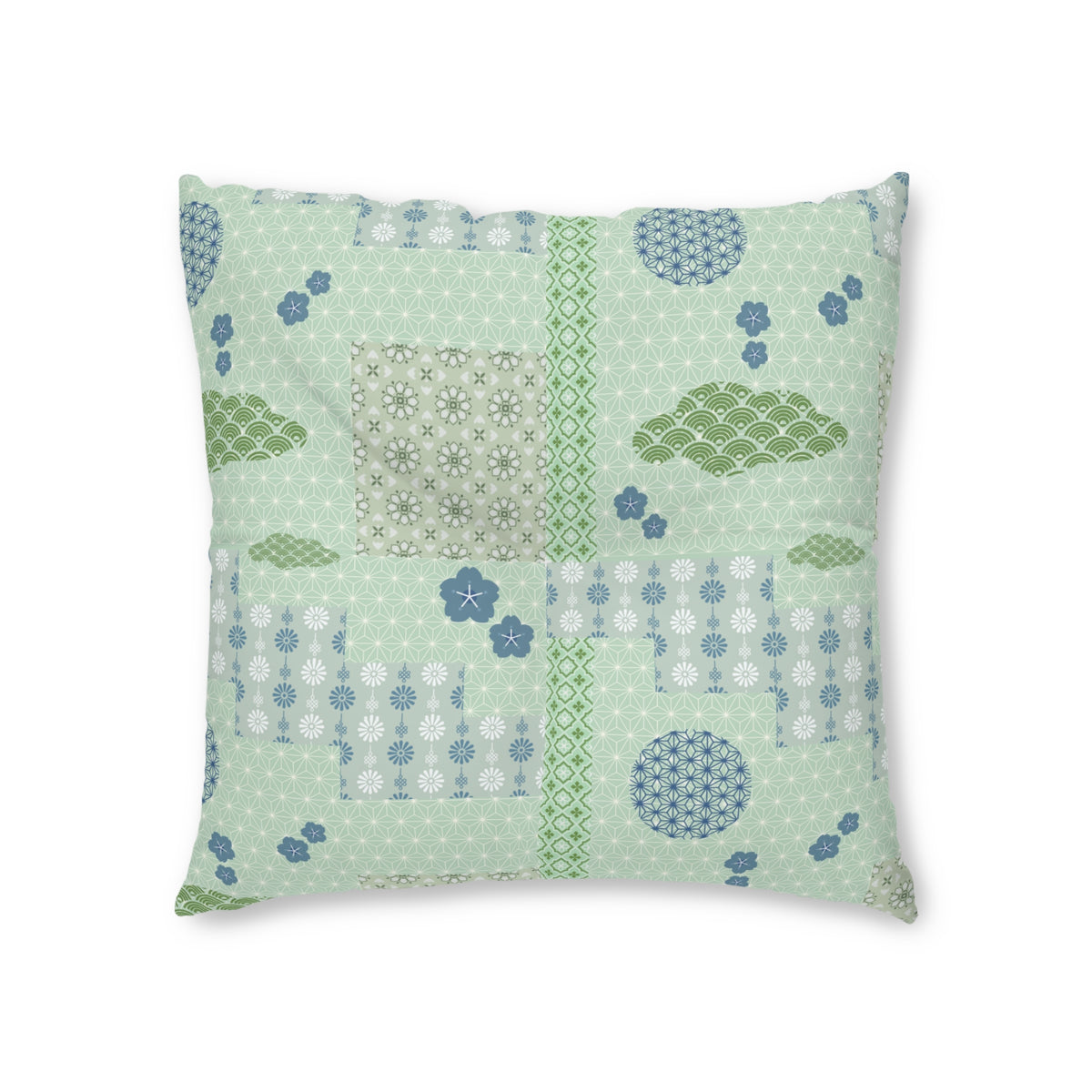A square decorative throw pillow featuring a patchwork design of light green, sage green, and blue patterns, including floral motifs, clouds, and geometric shapes, set against a plain white background.