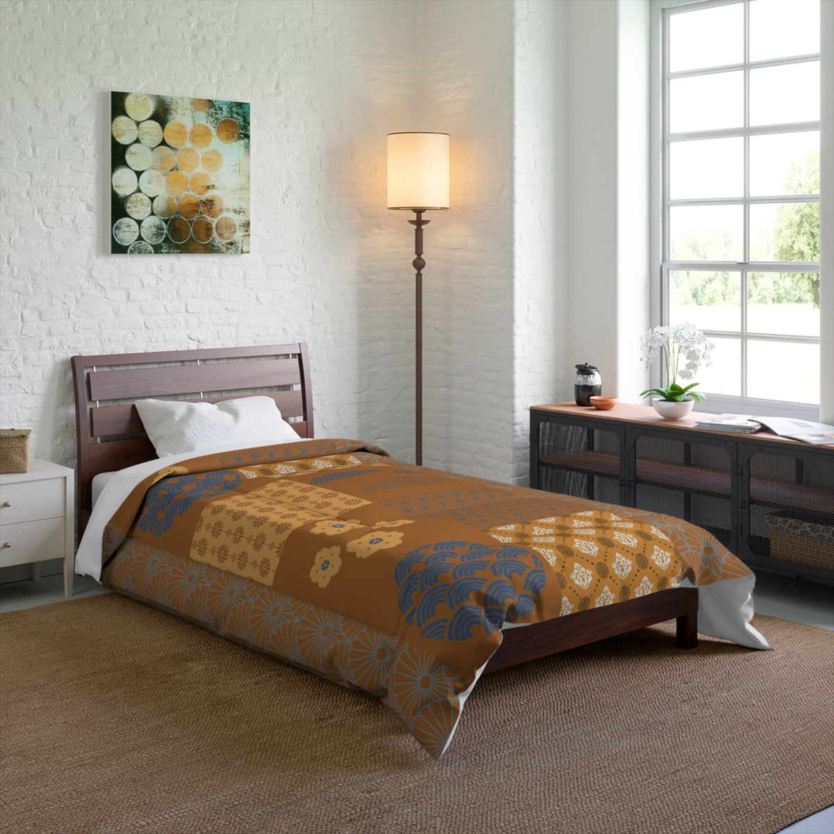 Bedroom with a bed covered in a patterned comforter, lamp, and artwork on the wall.