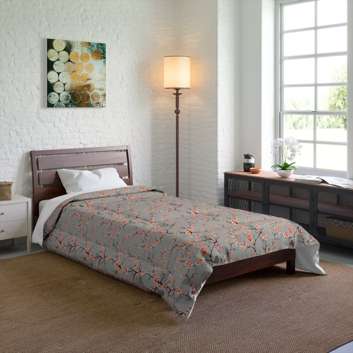 Bedroom with a bed featuring a gray comforter with orange floral patterns, a lamp, and a window.