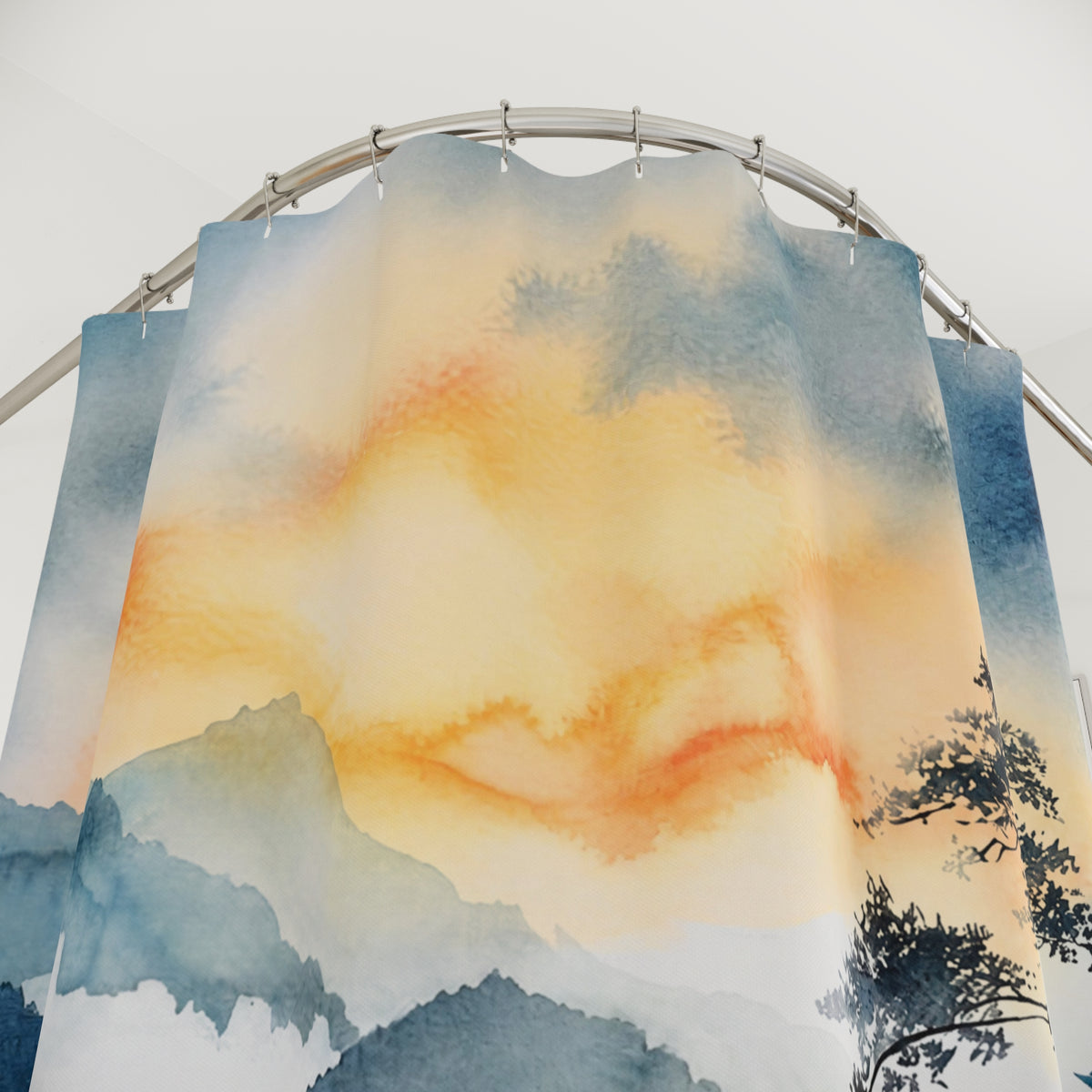Watercolor-style shower curtain hanging from a curved metal rod, featuring soft blue-gray mountains and trees with warm orange and cream sky tones.