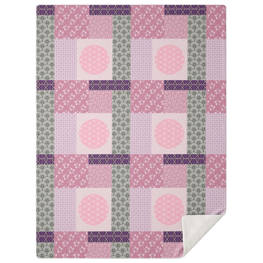 A high-angle, square photograph of a minimalist professional study featuring a dark walnut wood lounge chair. Neatly draped over the chair is the Maiko Dreams Patchwork Blanket from Kaito Japan Design. The blanket features a stunning patchwork of Sakura Pink, deep Magenta, and soft Rose tones, interspersed with traditional floral and geometric Wagara motifs. Natural morning light creates a calm and sophisticated atmosphere.