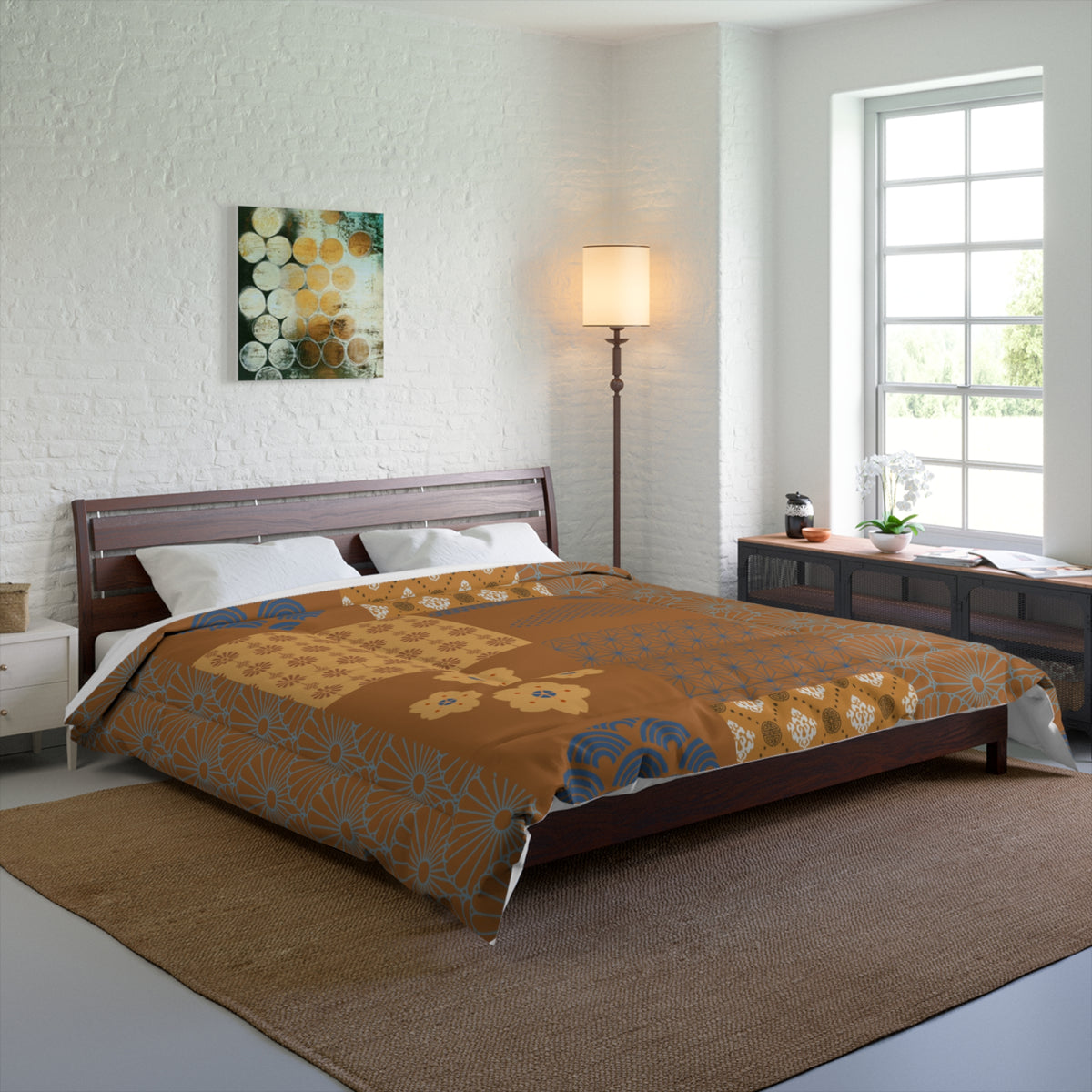 Bedroom with a bed covered in an orange floral comforter, lamp, and artwork on the wall.