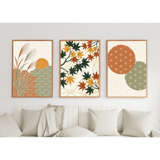 Three framed abstract and botanical wall art prints hang above a white sofa with neutral throw pillows in a bright, modern living room. The left print shows a sun over stylized grass and wave patterns in orange, green, and beige.