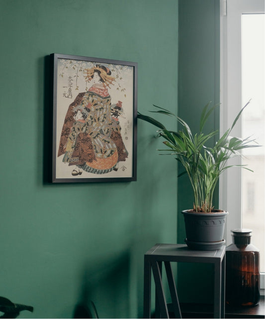 Framed artwork on a green wall with a plant and bottle in the foreground