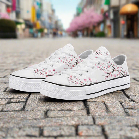 Classic white low-top canvas sneakers featuring an elegant all-over pink cherry blossom (Sakura) pattern with a white rubber toe cap and sole.