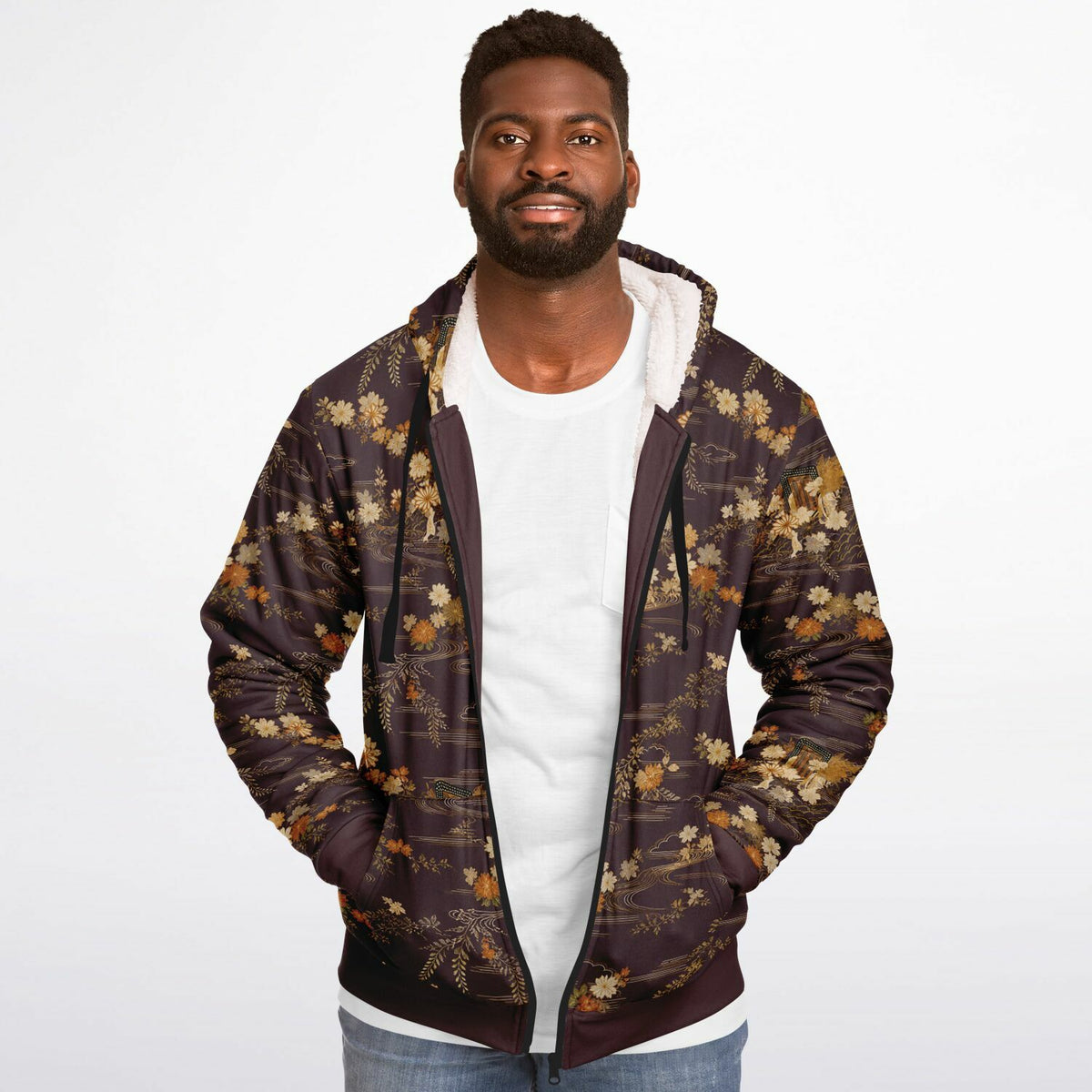 A man wearing a dark brown hooded jacket with a gold and beige floral pattern, layered over a white t-shirt and blue jeans, photographed against a solid white background.