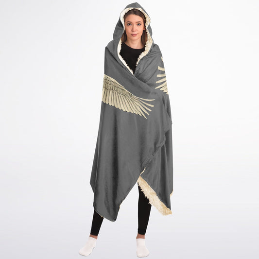 A person wrapped in a premium oversized hooded blanket featuring a vintage-style print of elegant white cranes in flight against a muted, heritage-toned background with sherpa lining