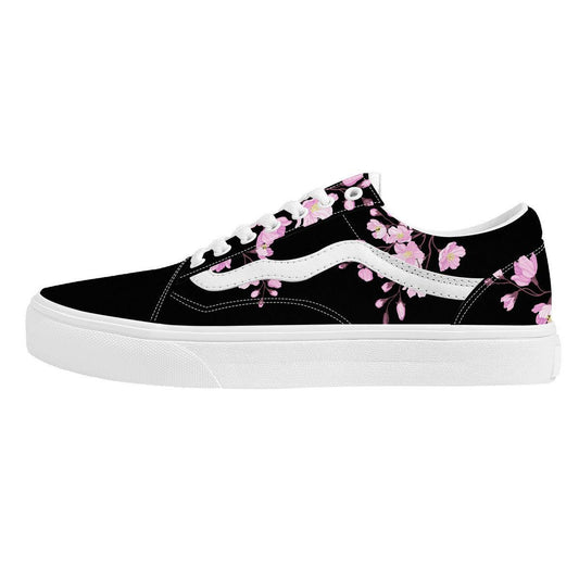 A pair of low-top sneakers with a black base color and a pink cherry blossom floral pattern, displayed against a red and black box.