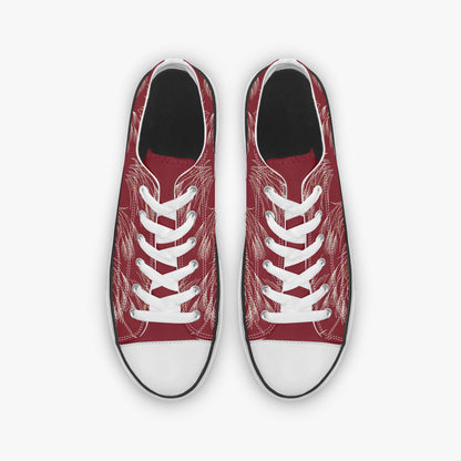 A pair of low-top canvas sneakers shown from a top-down view. The uppers are a deep red with a white sketch-style line art pattern, featuring white laces and white rubber toe caps.