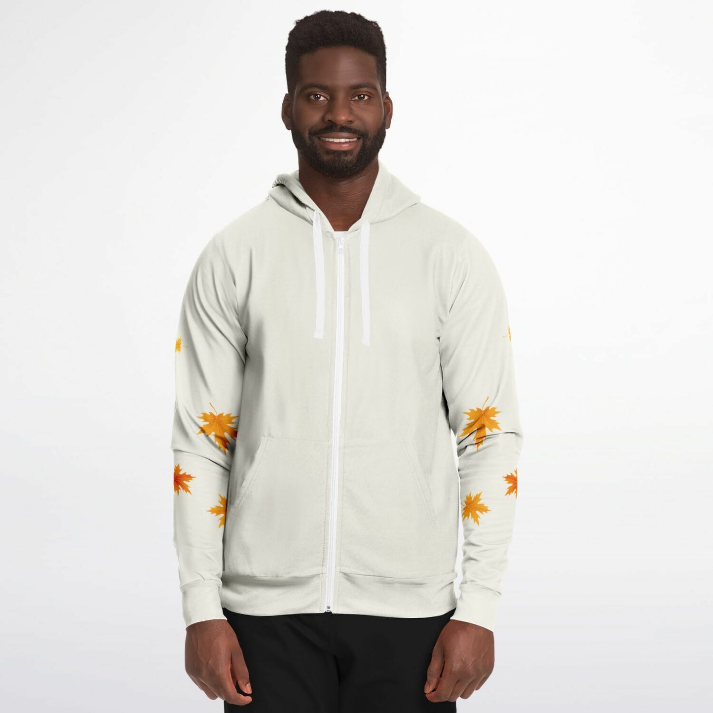 A man wearing a light beige zip-up hoodie with white drawstrings and orange leaf prints on the sleeves, paired with black pants, against a plain white background.