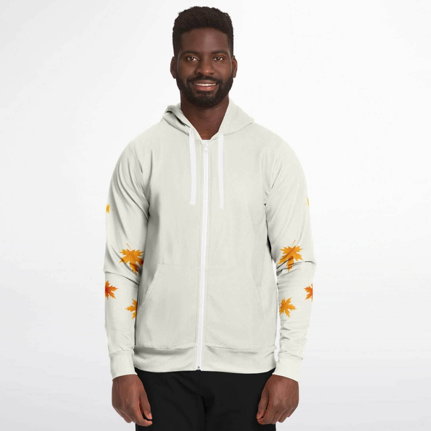 A man wearing a light beige zip-up hoodie with white drawstrings and orange leaf prints on the sleeves, paired with black pants, against a plain white background.