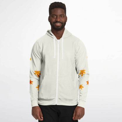 A man wearing a light beige zip-up hoodie with white drawstrings and orange leaf prints on the sleeves, paired with black pants, against a plain white background.