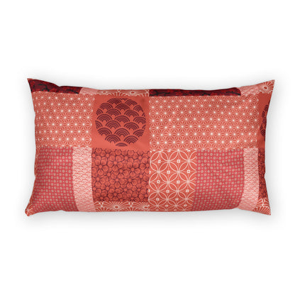 A rectangular lumbar pillow featuring a patchwork design of various red and pink Japanese patterns, including houndstooth, wave, and geometric motifs, set against a plain white background.
