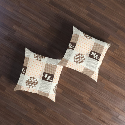 Two square throw pillows with a beige, brown, and white patchwork pattern featuring geometric and dotted motifs, displayed on a dark wood floor.