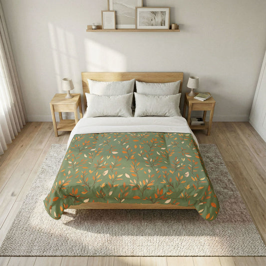 A neatly made bed in a bright, modern bedroom, featuring a sage green comforter with an orange and beige leaf pattern, white sheets, and a light wood headboard and nightstands.