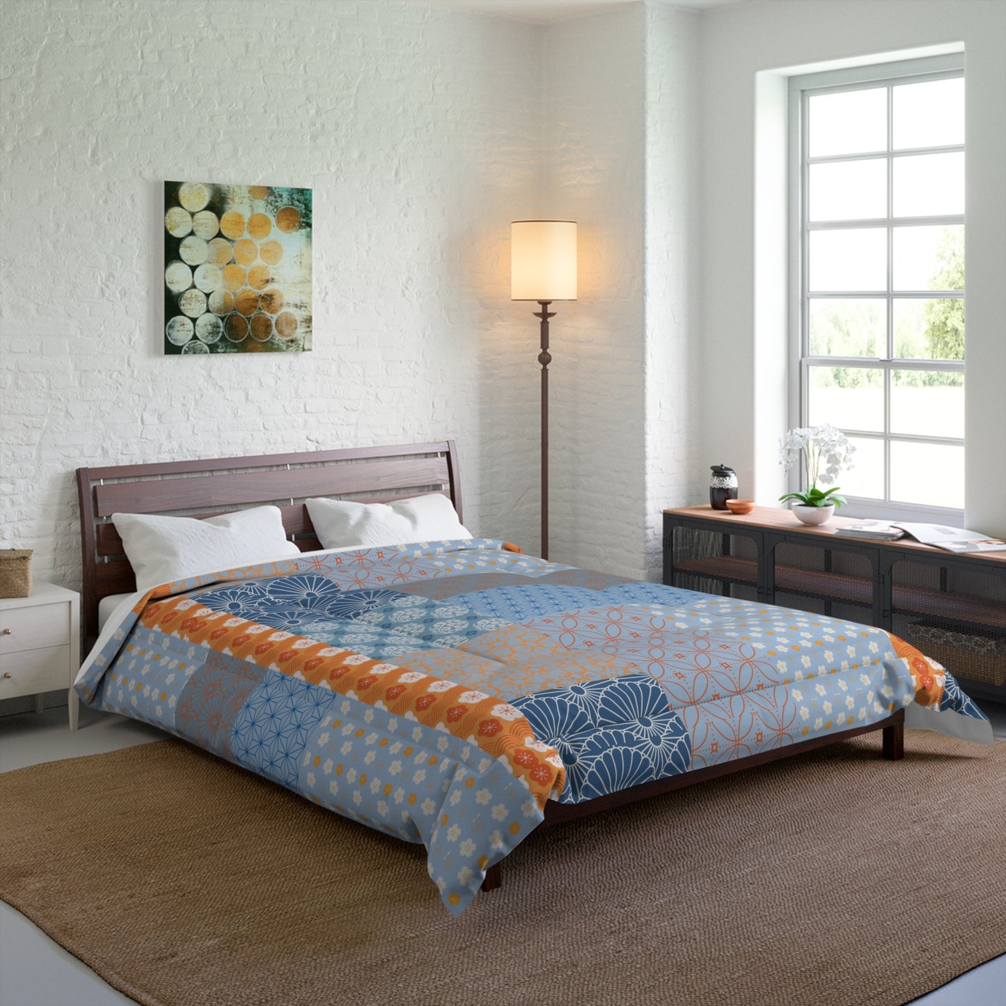 Bedroom with a bed featuring a blue and orange patterned comforter, a lamp, and a painting on the wall.
