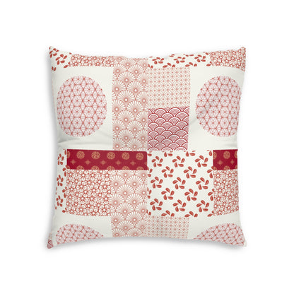 A square decorative throw pillow featuring a patchwork design of red and pink Japanese-inspired patterns on an off-white background, set against a plain white studio backdrop.