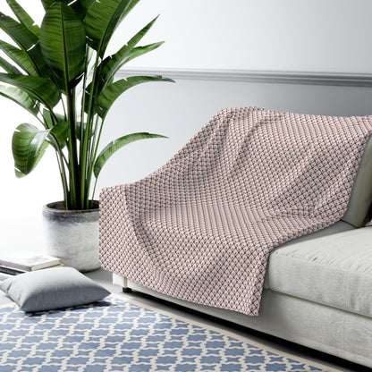 Gray patterned throw blanket draped over a sofa in a living room with a plant and rug.