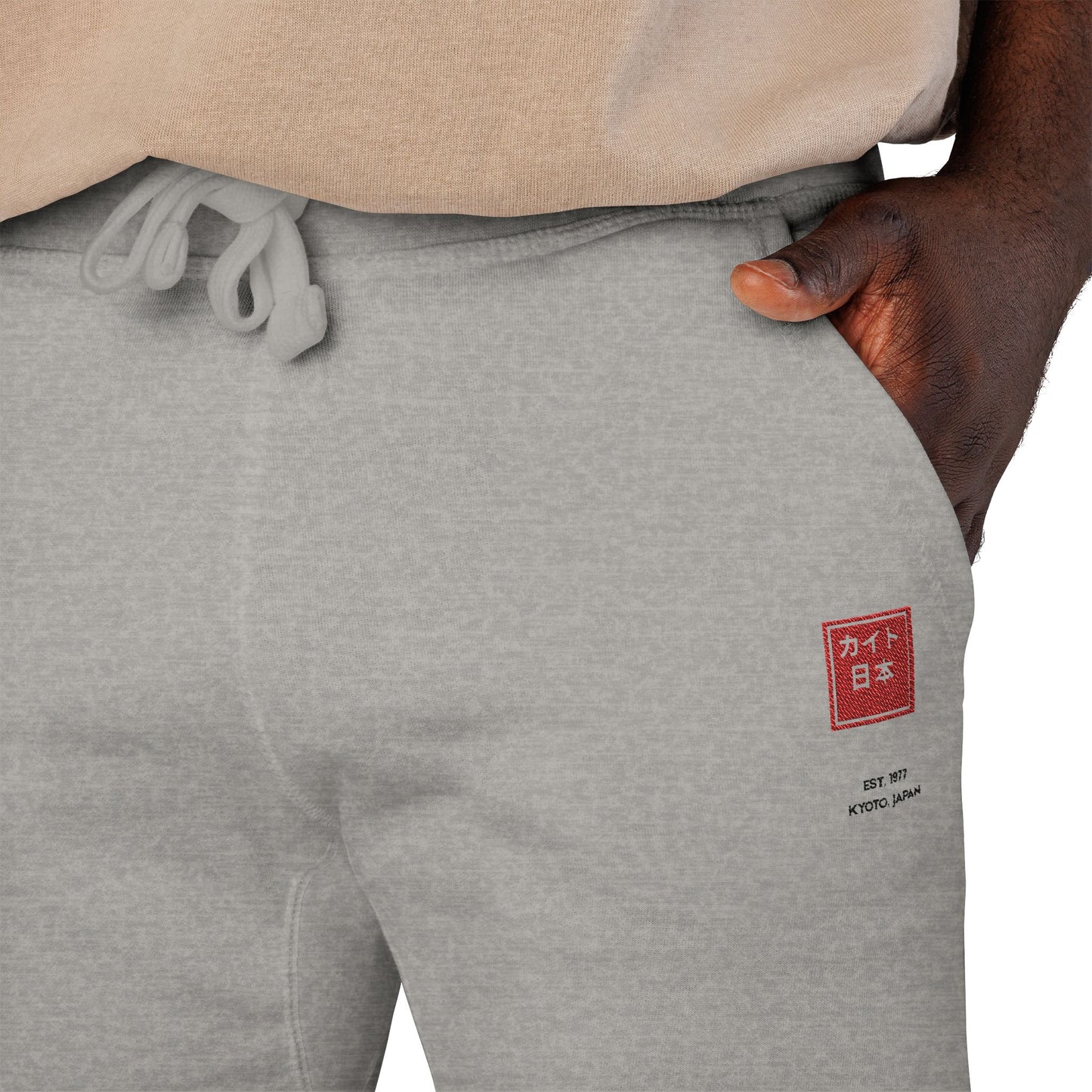 Gray sweatpants with a red and white logo on the left leg, worn by a person.
