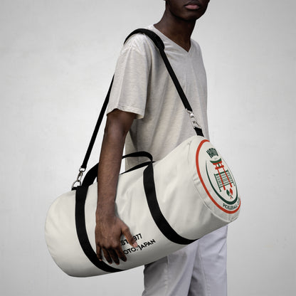 Person holding a white duffel bag with branding against a plain background