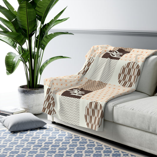 Patterned throw blanket draped over a sofa in a living room with a plant and rug.