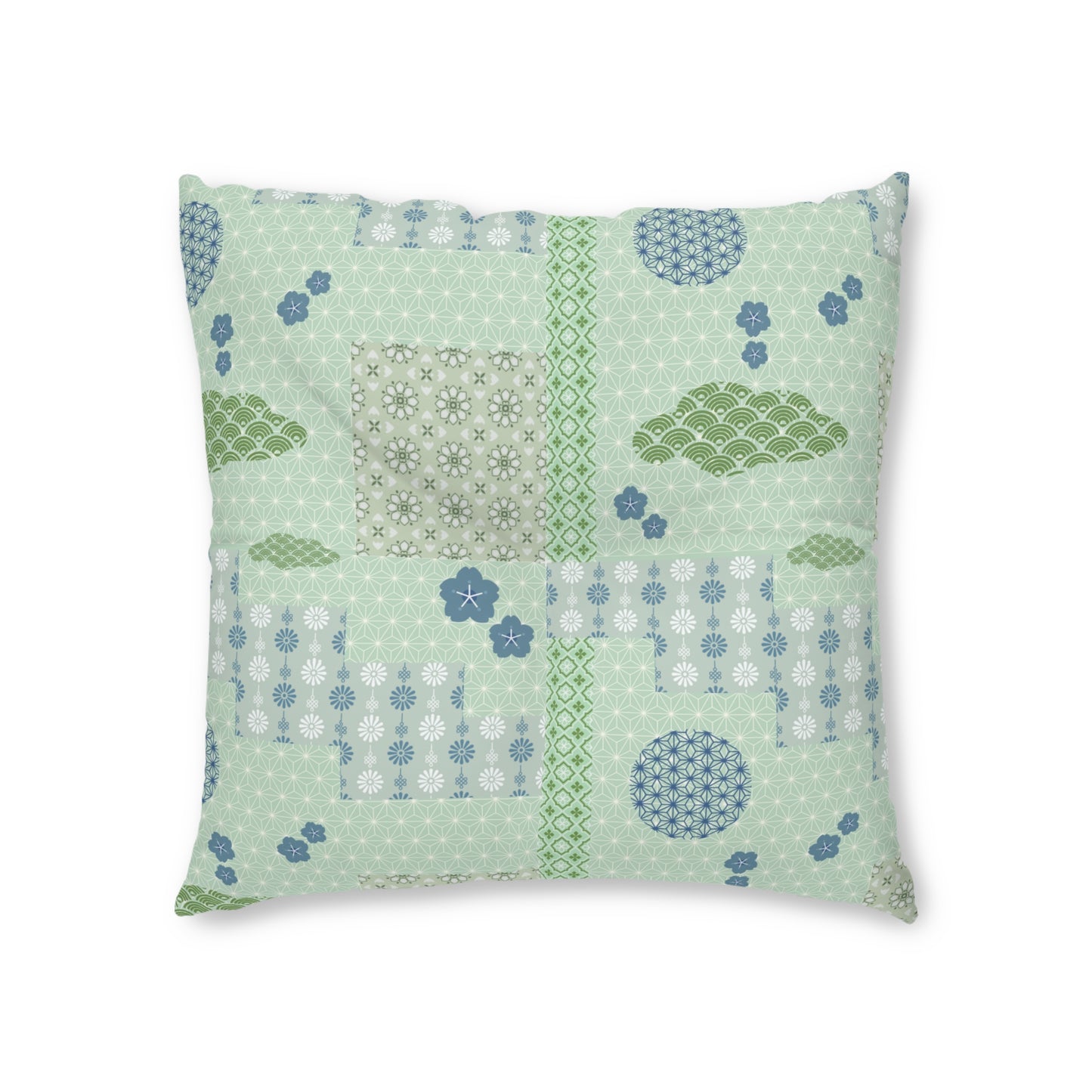 A square decorative throw pillow featuring a patchwork design of light green, sage green, and blue patterns, including floral motifs, clouds, and geometric shapes, set against a plain white background.