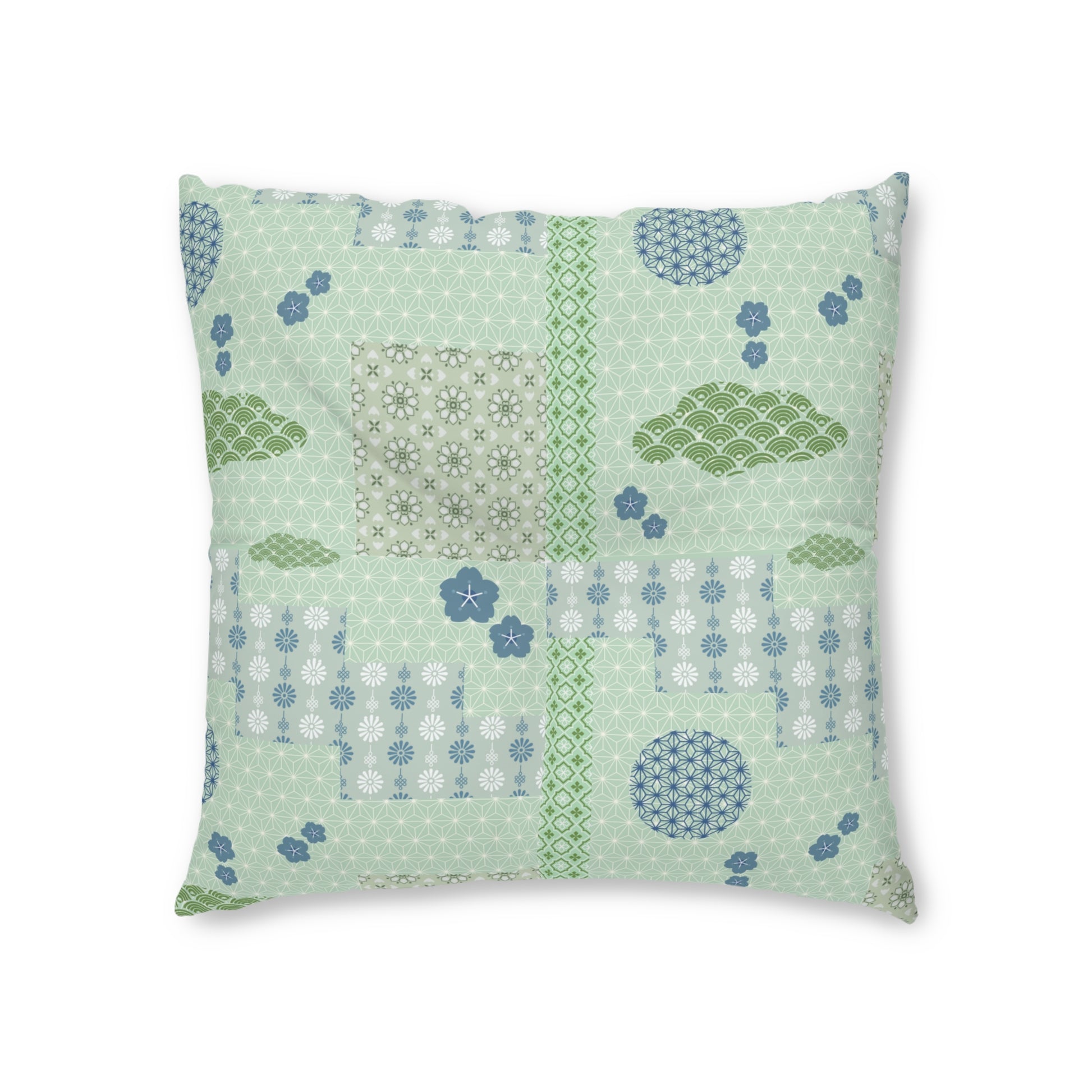 A square decorative throw pillow featuring a patchwork design of light green, sage green, and blue patterns, including floral motifs, clouds, and geometric shapes, set against a plain white background.