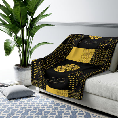 Black and yellow patterned sofa cover draped over a white sofa with a plant in the background.
