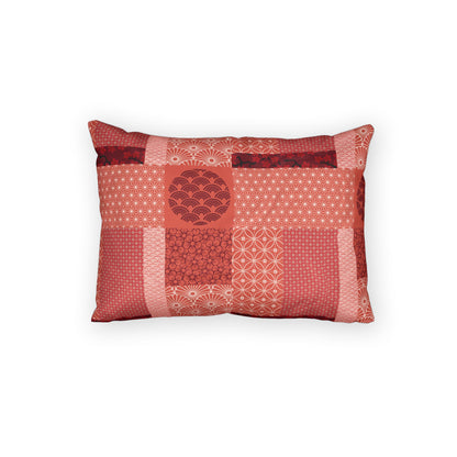A rectangular decorative throw pillow featuring a patchwork design of various red and pink Japanese patterns, including ikat, wave motifs, and geometric prints, set against a plain white background.