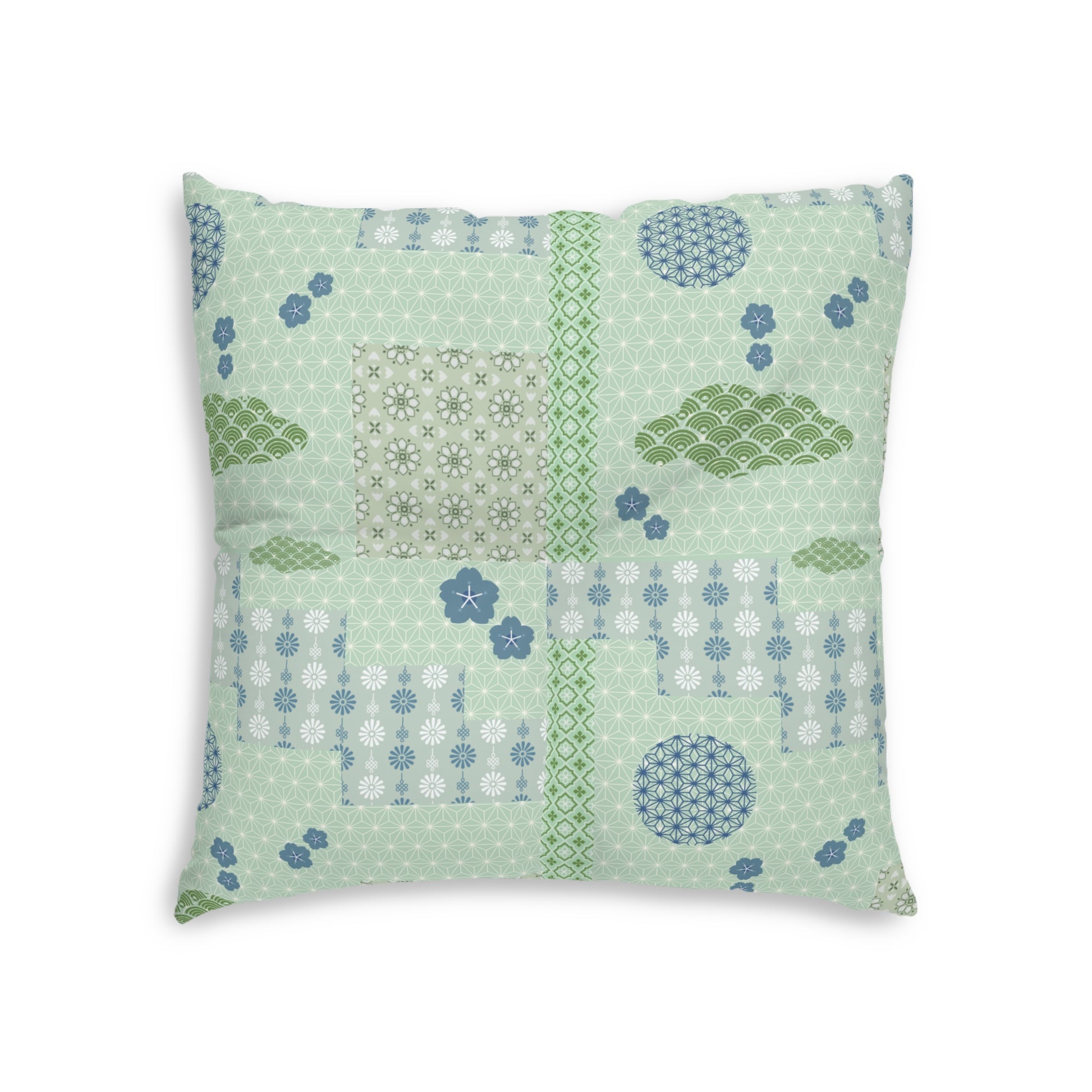 A square decorative throw pillow featuring a patchwork quilted design in shades of sage green, light blue, and white, set against a plain white background.