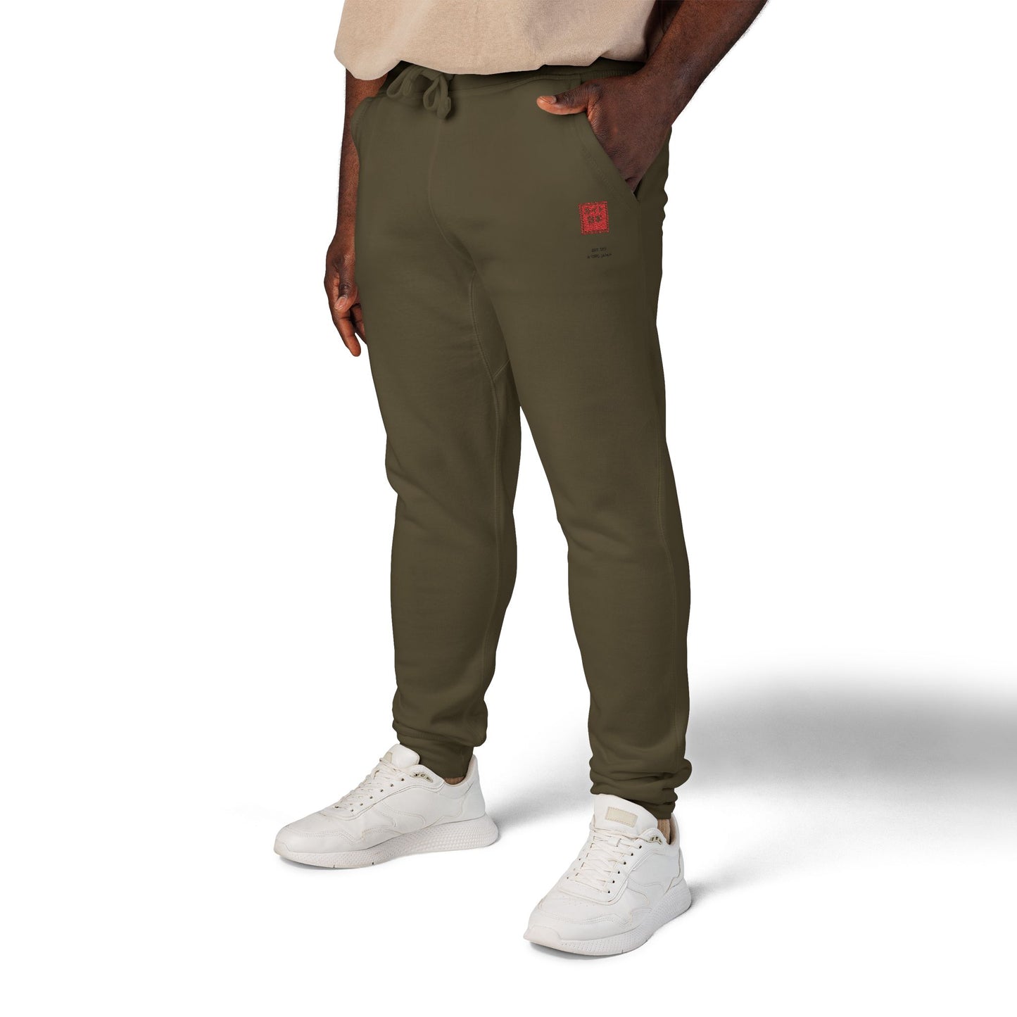 Person wearing olive green jogger pants and white sneakers on a white background