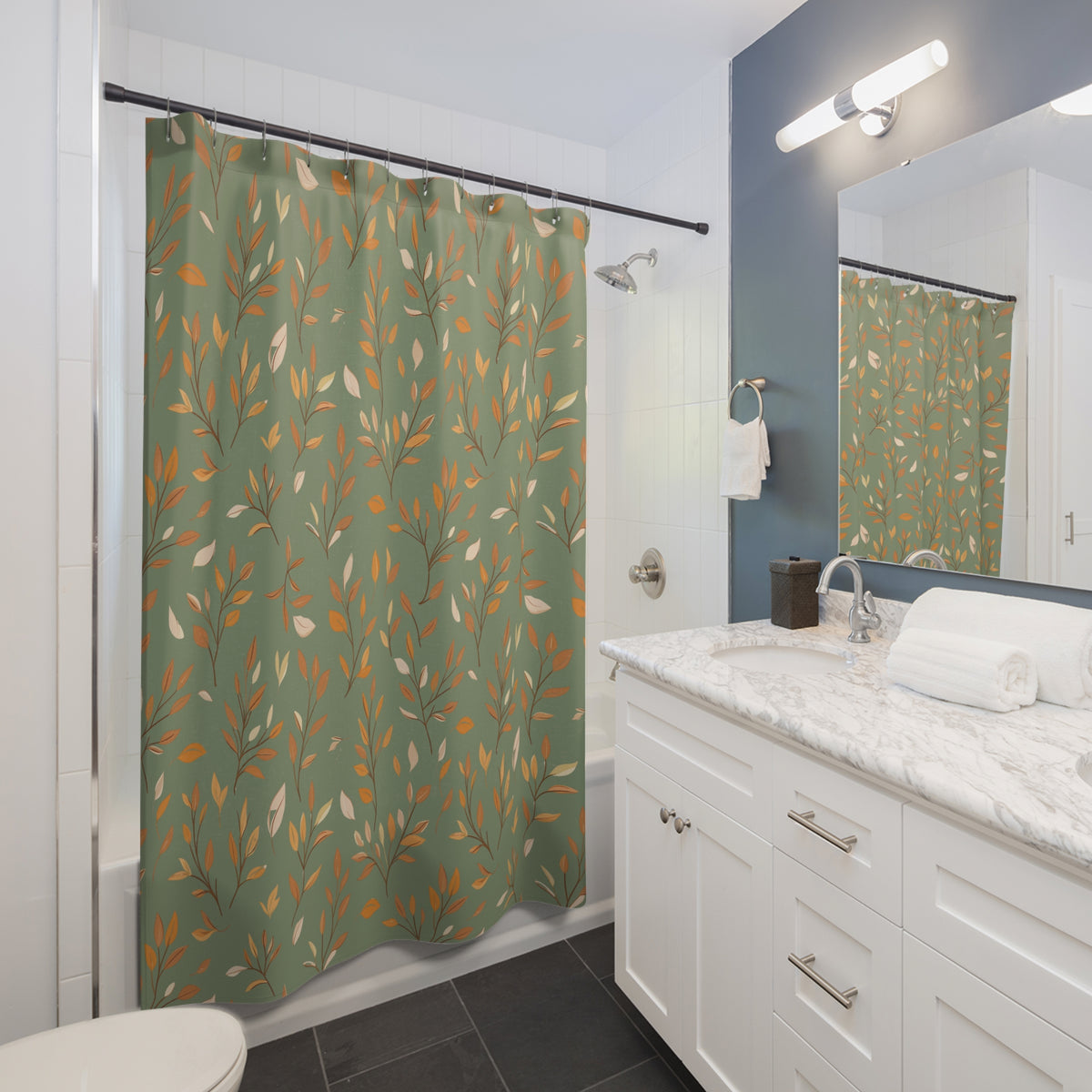A green shower curtain with a repeating pattern of orange and cream leaves hanging in a modern white bathroom with a marble countertop and dark gray tile floor.
