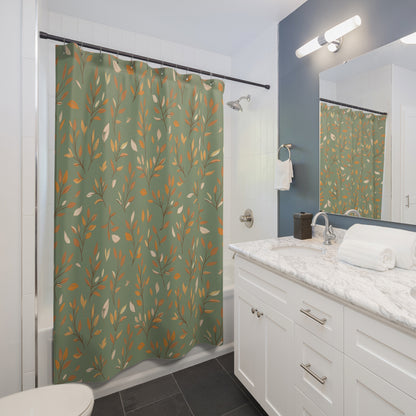 A green shower curtain with a repeating pattern of orange and cream leaves hanging in a modern white bathroom with a marble countertop and dark gray tile floor.