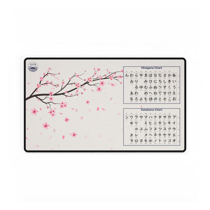 Deskmat with cherry blossom design and Japanese character charts on a white background