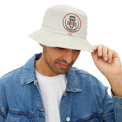 Man wearing a white bucket hat with a logo, paired with a blue denim jacket on a white background