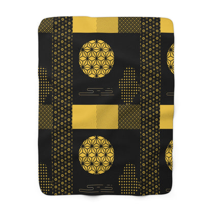 Black blanket with gold geometric patterns on a white background