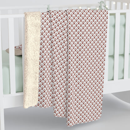 Red and white patterned blanket draped over a crib with a white crib in the background.