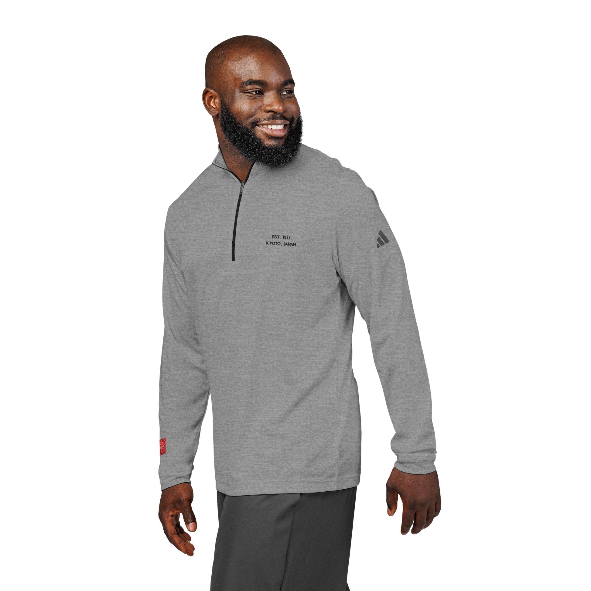 Man wearing a gray Adidas pullover with a logo on a white background