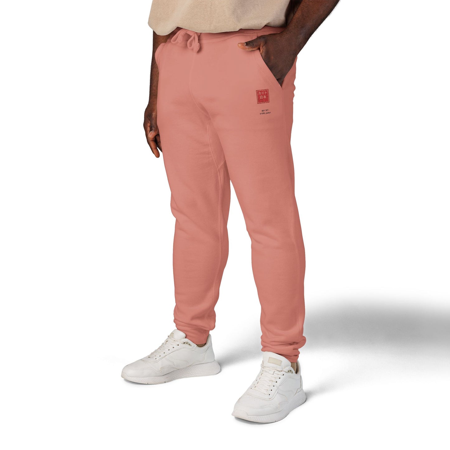 Person wearing pink jogger pants and white sneakers on a white background