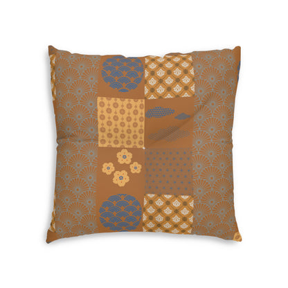 A square decorative throw pillow featuring a patchwork design of various Japanese-inspired patterns in warm brown, beige, and muted blue-gray tones, shown against a plain white background.