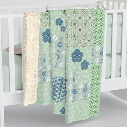 Set of green and blue patterned baby blankets hanging on a crib