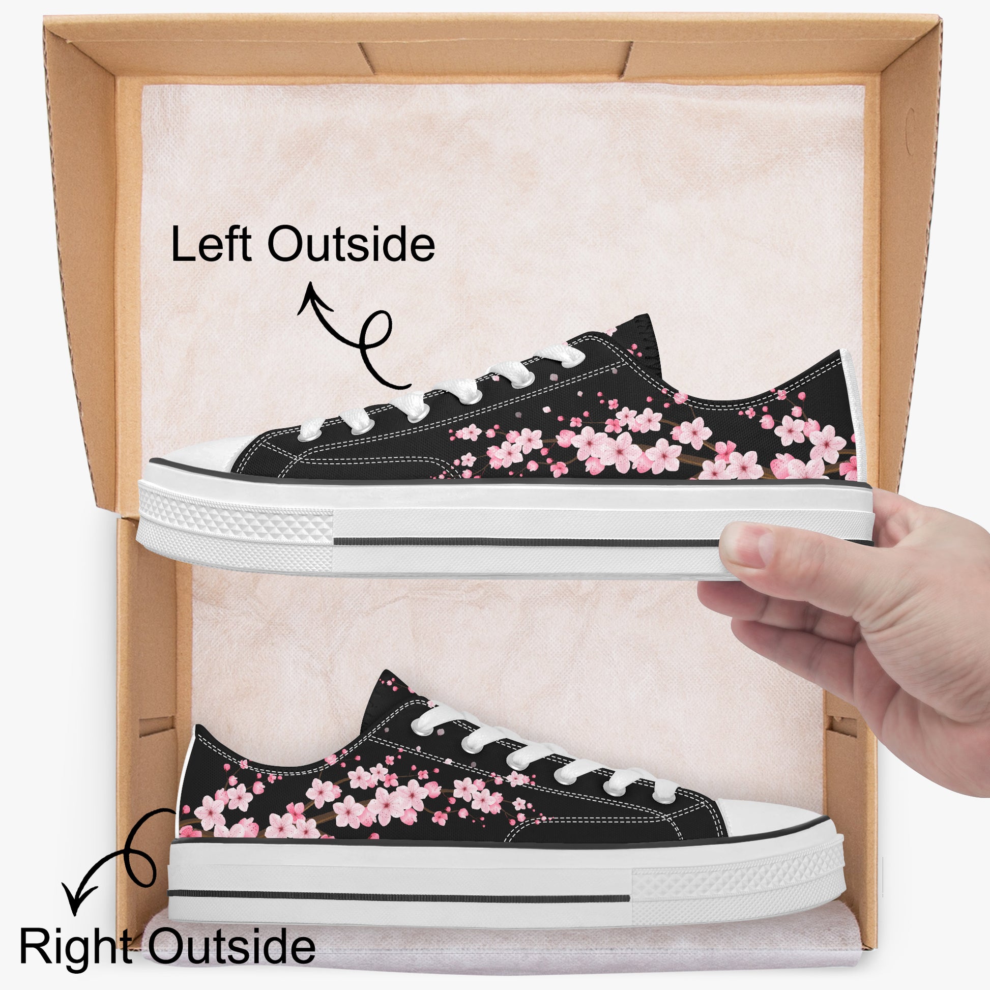 Black sneakers with pink floral pattern on a cardboard box, held by a hand.