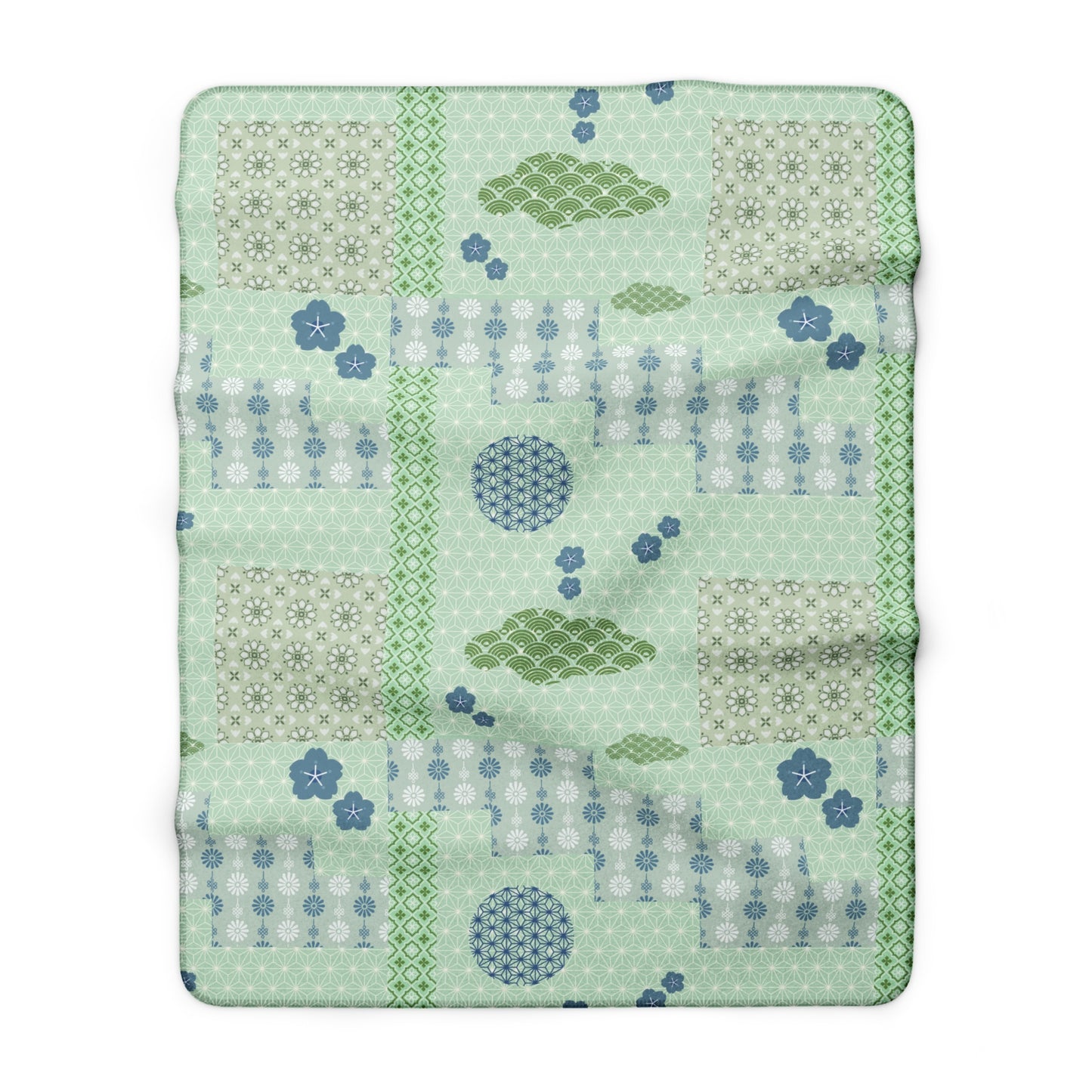 Patchwork quilt with green and blue patterns on a white background