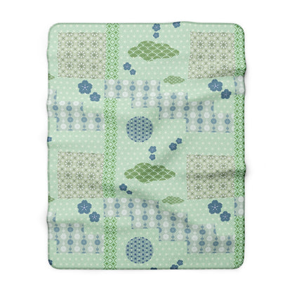 Patchwork quilt with green and blue patterns on a white background
