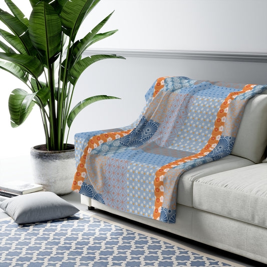 Decorative throw blanket with geometric pattern on a sofa in a living room setting.