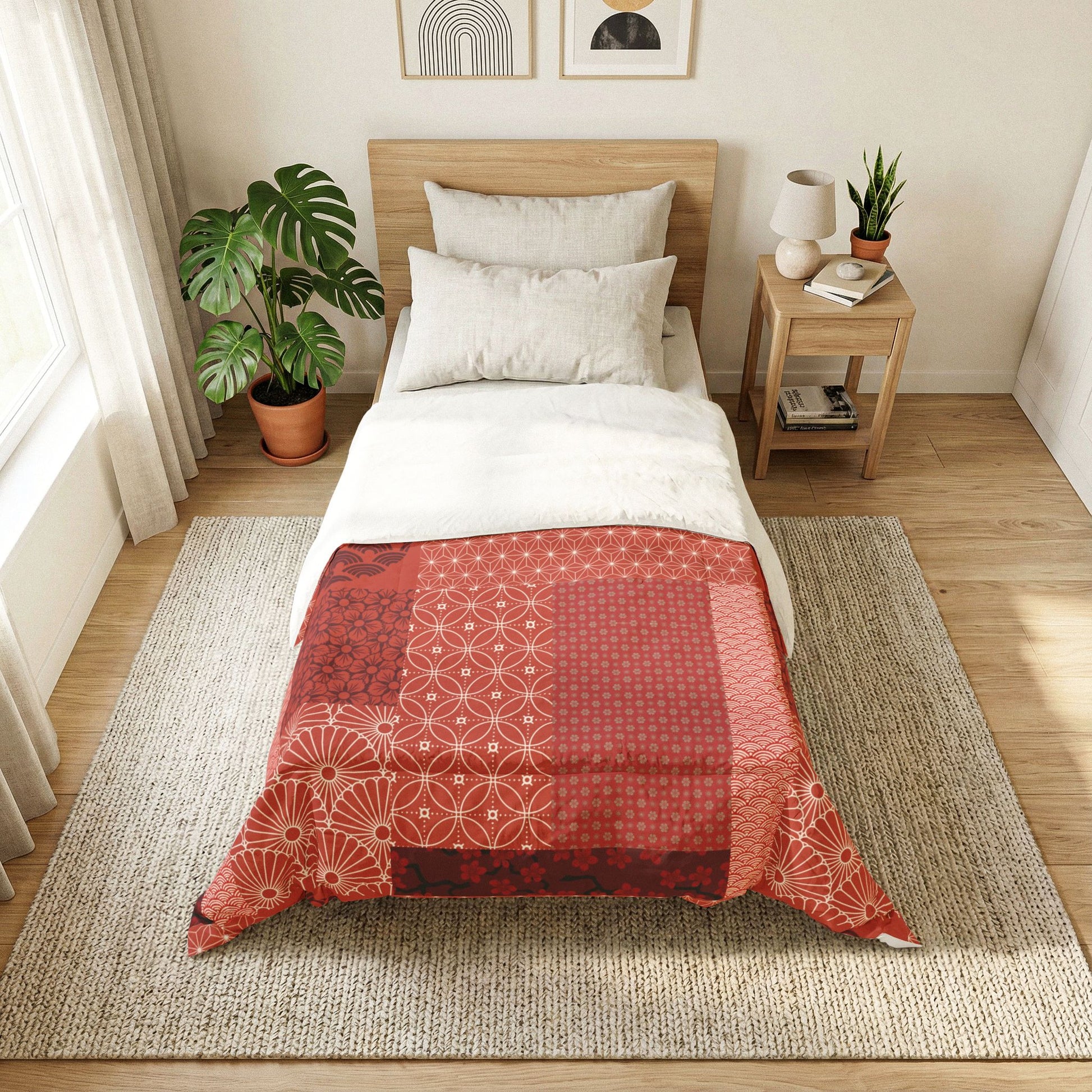 Bedroom with a bed featuring a red and white patterned comforter, side table with lamp and books, and plants. Cotton Heritage