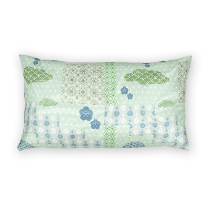 A rectangular lumbar pillow featuring a patchwork design of light green, sage, and blue patterns including clouds, flowers, and geometric motifs, set against a plain white background.