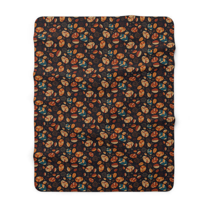 A rectangular throw blanket with a dark charcoal background covered in a dense, repeating pattern of illustrated pumpkins and gourds in orange, brown, and teal, shown flat against a solid white background.