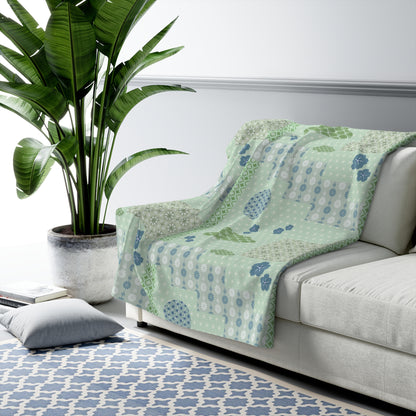 Green floral-patterned blanket on a gray sofa with a plant and rug in the background
